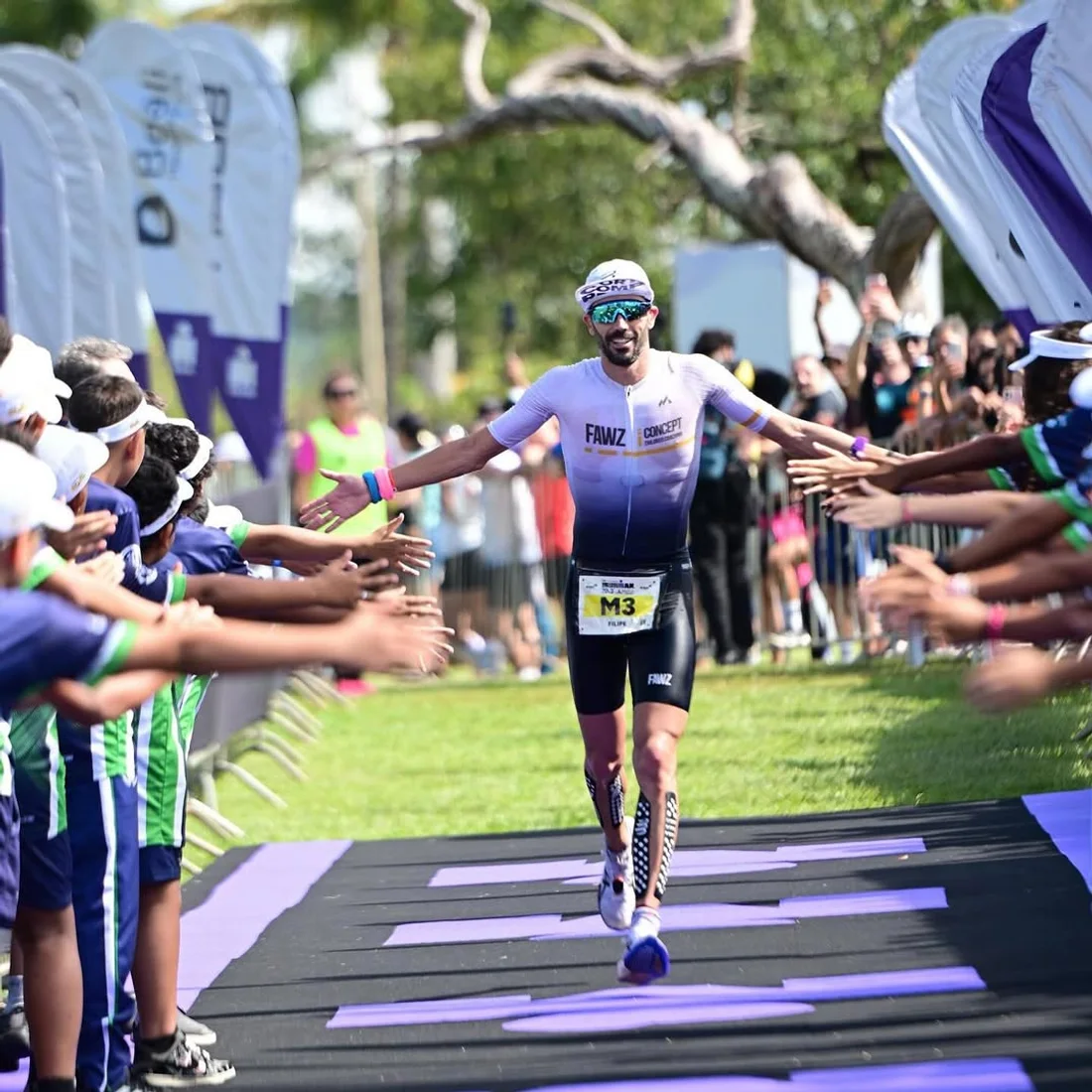 Filipe Azevedo high-fiving the crowd in the finish chute at IRONMAN 70.3 Brasilia 2026, where he finished second