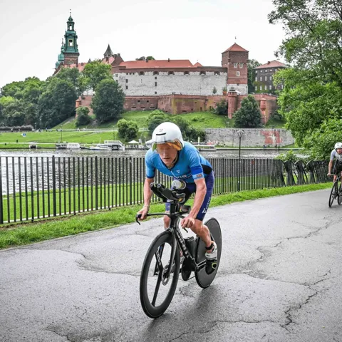 Thomas Davis on his time trial bike beside the Vistula, below Wawel Castle in Kraków